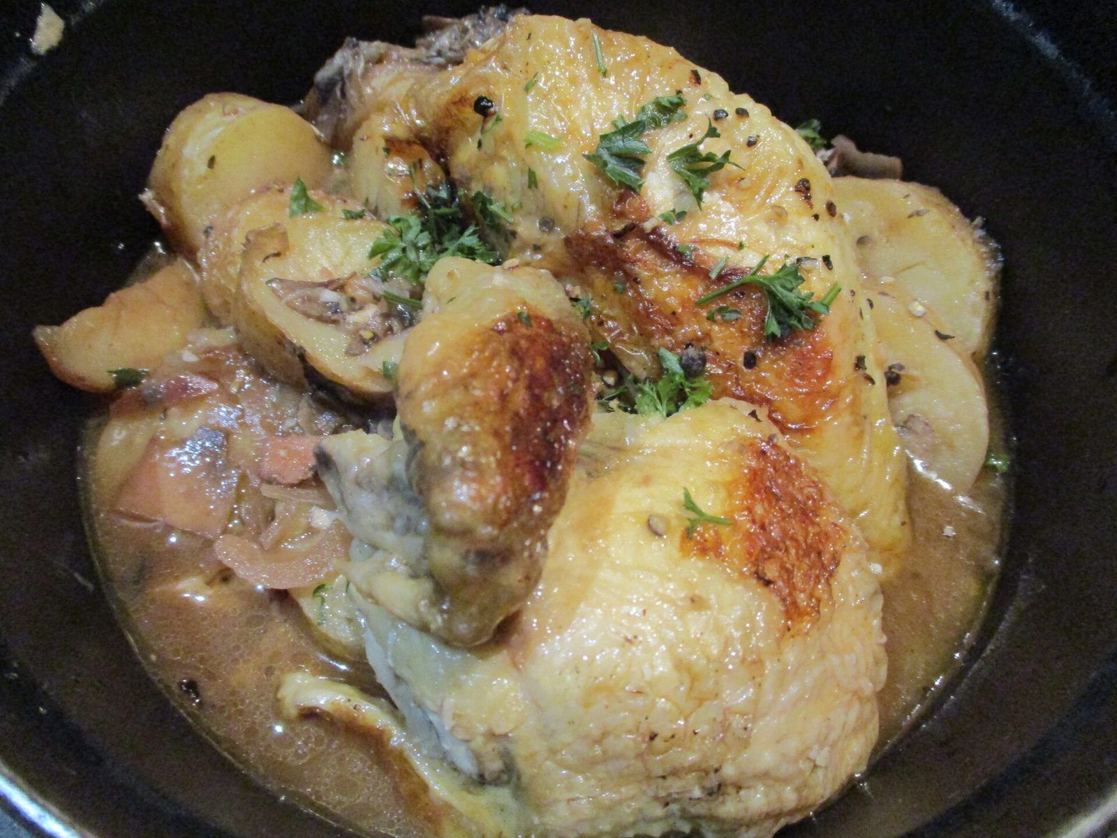 Poulet doré mijoté au vinaigre avec des pommes de terre dans une cocotte en fonte