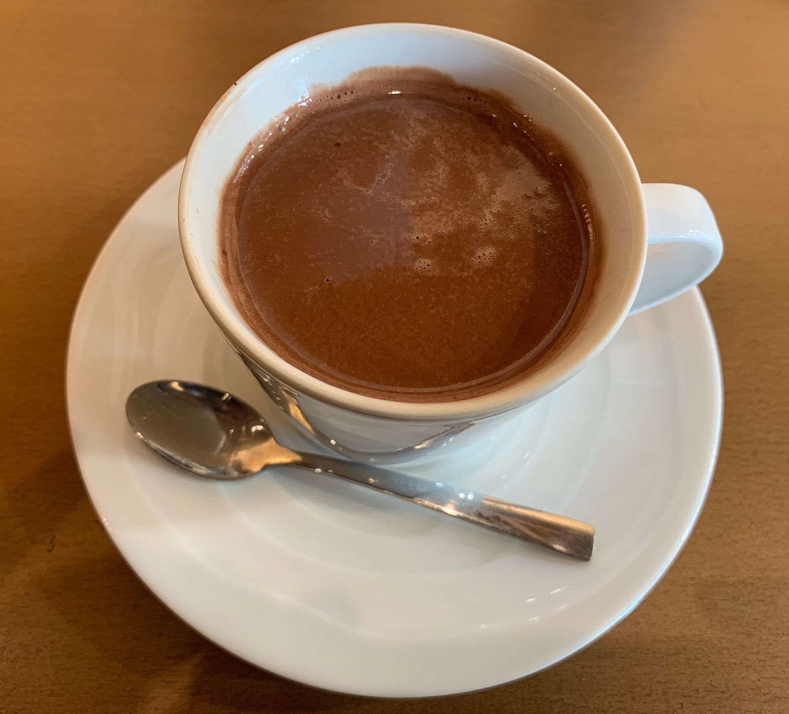 Tasse de chocolat chaud sur une soucoupe blanche, avec sa petite cuillère