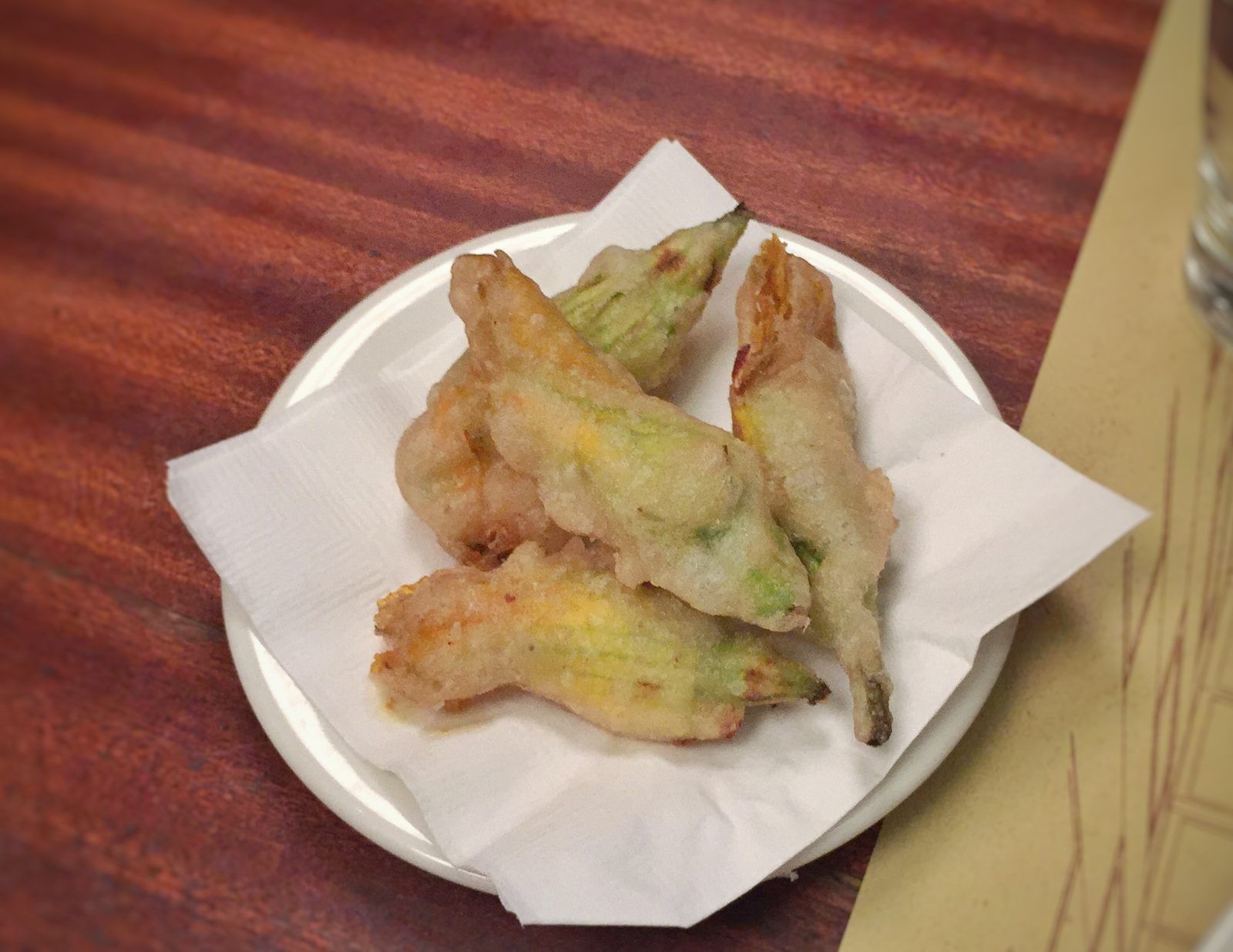 Beignets de fleurs de courgette sur une petite assiette garnie d'une serviette en papier