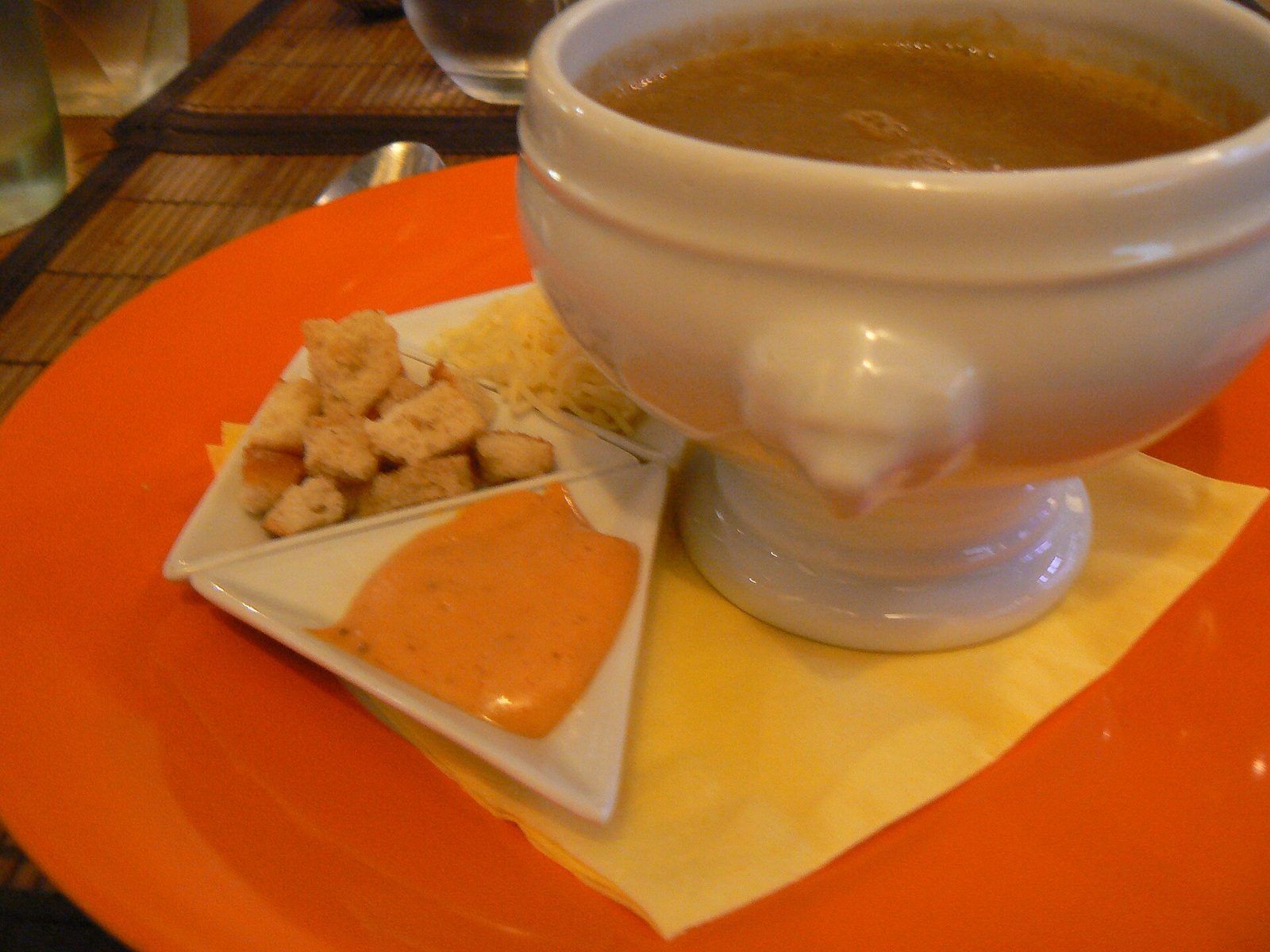 Soupe de poissons dans un bol à pied, servie avec la rouille, des croûtons et du fromage râpé