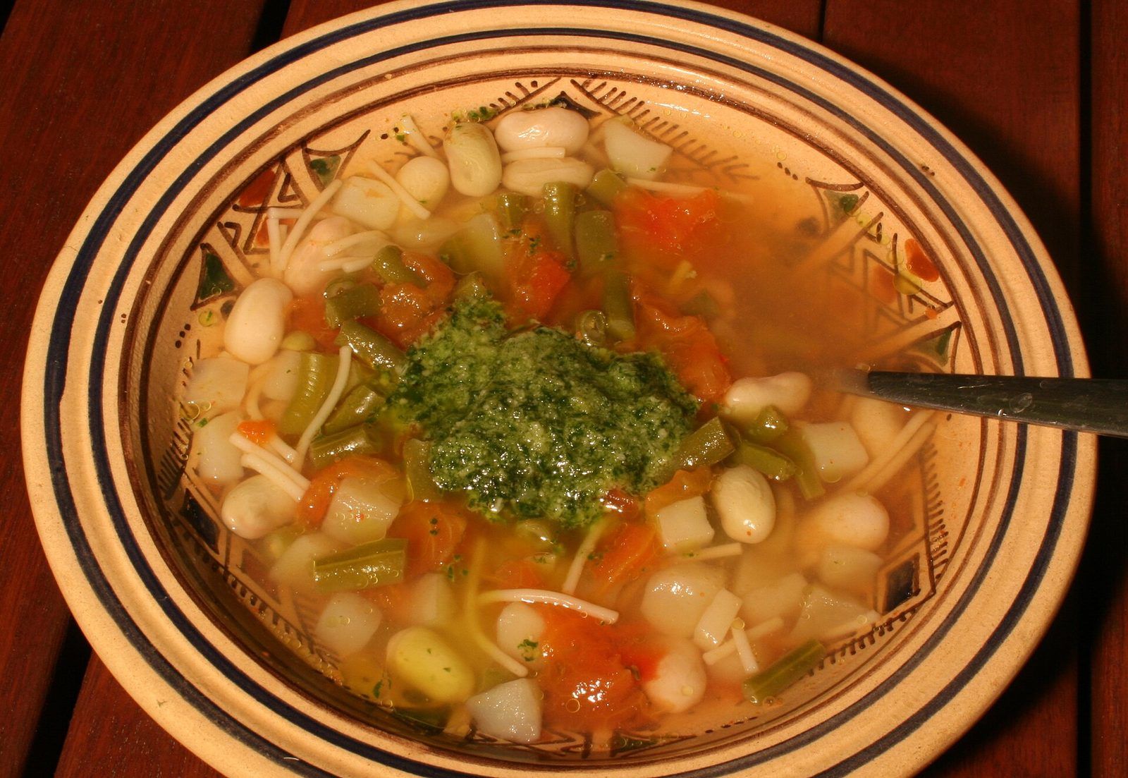 Assiette de soupe au pistou avec haricots blancs, haricots verts, vermicelles et une cuillerée de pistou