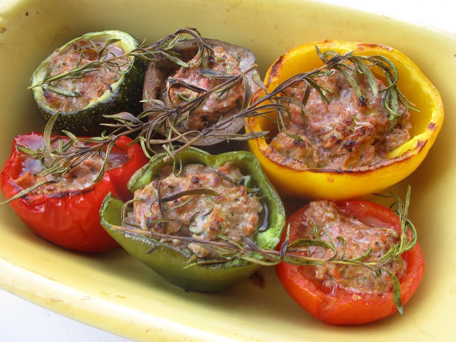 Tomates, poivrons, courgettes et aubergine farcis au romarin dans un plat à four